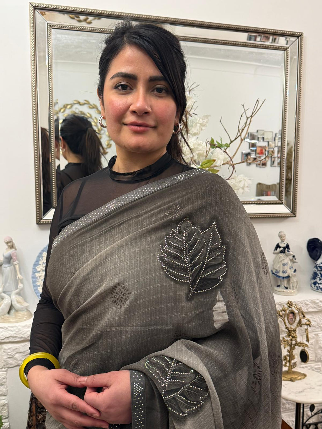 A mud grey chiffon saree adorned with delicate stone work,intricately arranged in graceful leafy ,motifs,lending it a refined and sophisticated charm.£55