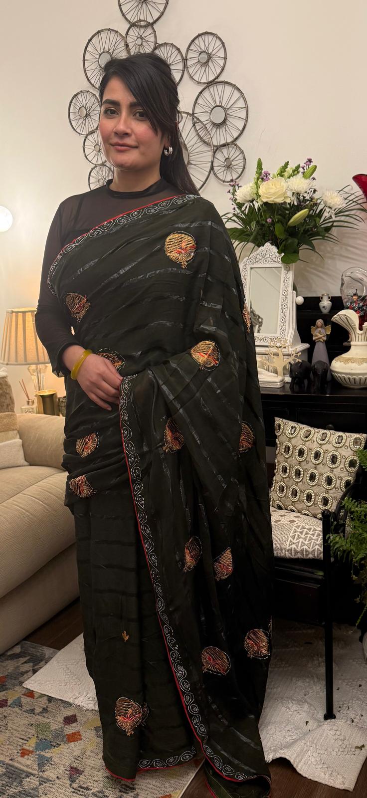 A mud grey chiffon saree adorned with delicate stone work,intricately arranged in graceful leafy ,motifs,lending it a refined and sophisticated charm.£55