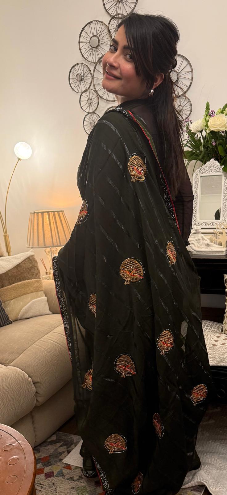 A mud grey chiffon saree adorned with delicate stone work,intricately arranged in graceful leafy ,motifs,lending it a refined and sophisticated charm.£55