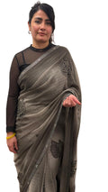 A mud grey chiffon saree adorned with delicate stone work,intricately arranged in graceful leafy ,motifs,lending it a refined and sophisticated charm.£55