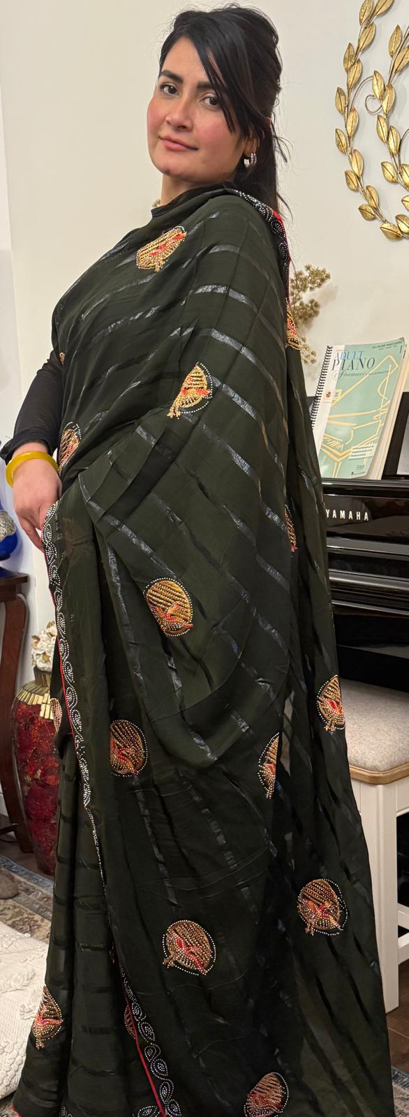 This army green silk chiffon blend saree is light, airy and effortlessly stylish,featuring fine horizontal lines and charming embroidered motifs.A balance of modern chic and timeless elegance £55