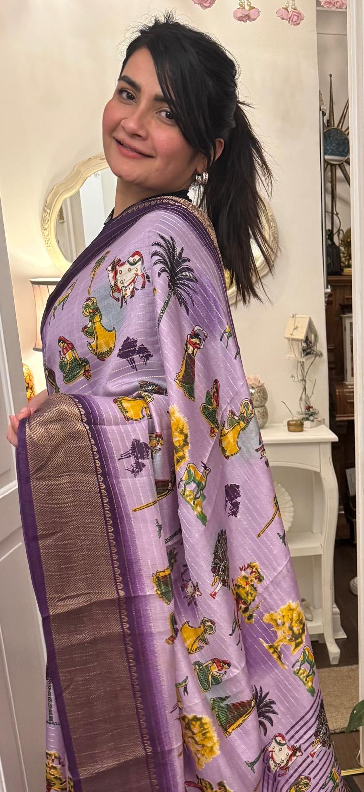 A lavender silk saree with a rich plum border delicately detailed with subtle zari work throughout. Showcasing ethnic, folk- inspired drawings that reflects culture and place with timeless pride. £80 tbc