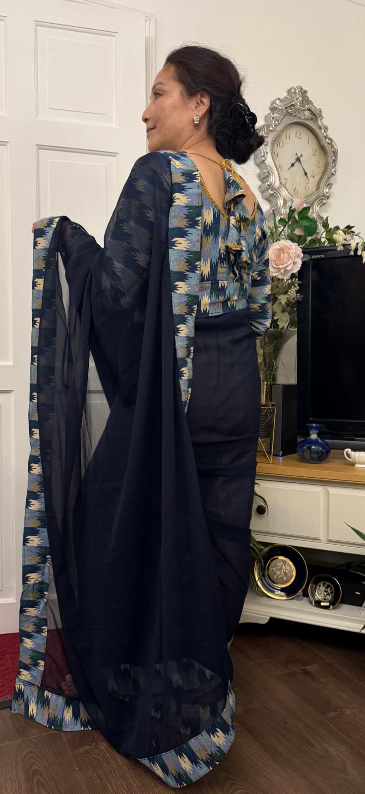 A midnight blue georgette saree beautifully detailed with Dhaka print border in a lighter tonal shade. Complimented by a matching blouse.This ensemble is truly unique and graceful, effortlessly maintaining a smart and elegant appeal. £135