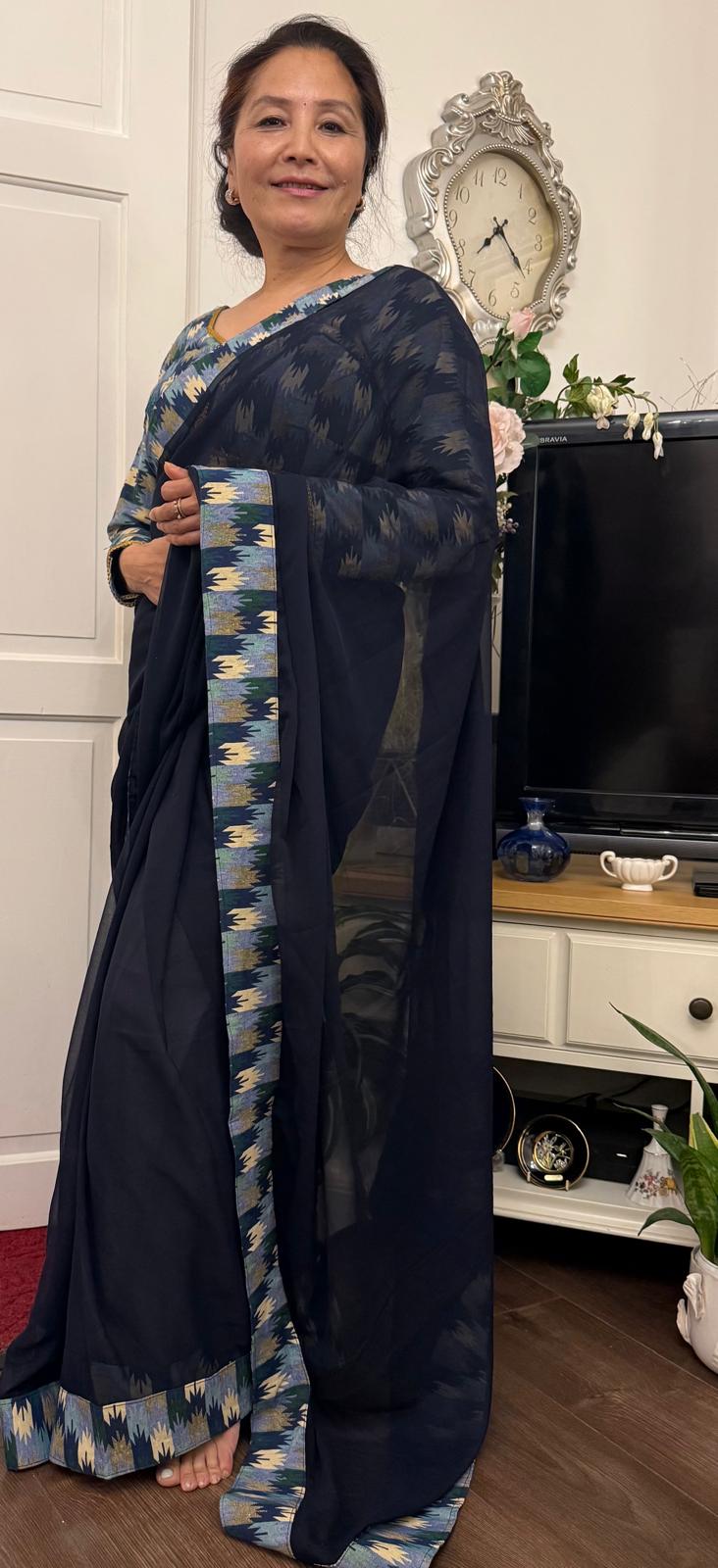 A midnight blue georgette saree beautifully detailed with Dhaka print border in a lighter tonal shade. Complimented by a matching blouse.This ensemble is truly unique and graceful, effortlessly maintaining a smart and elegant appeal. £135